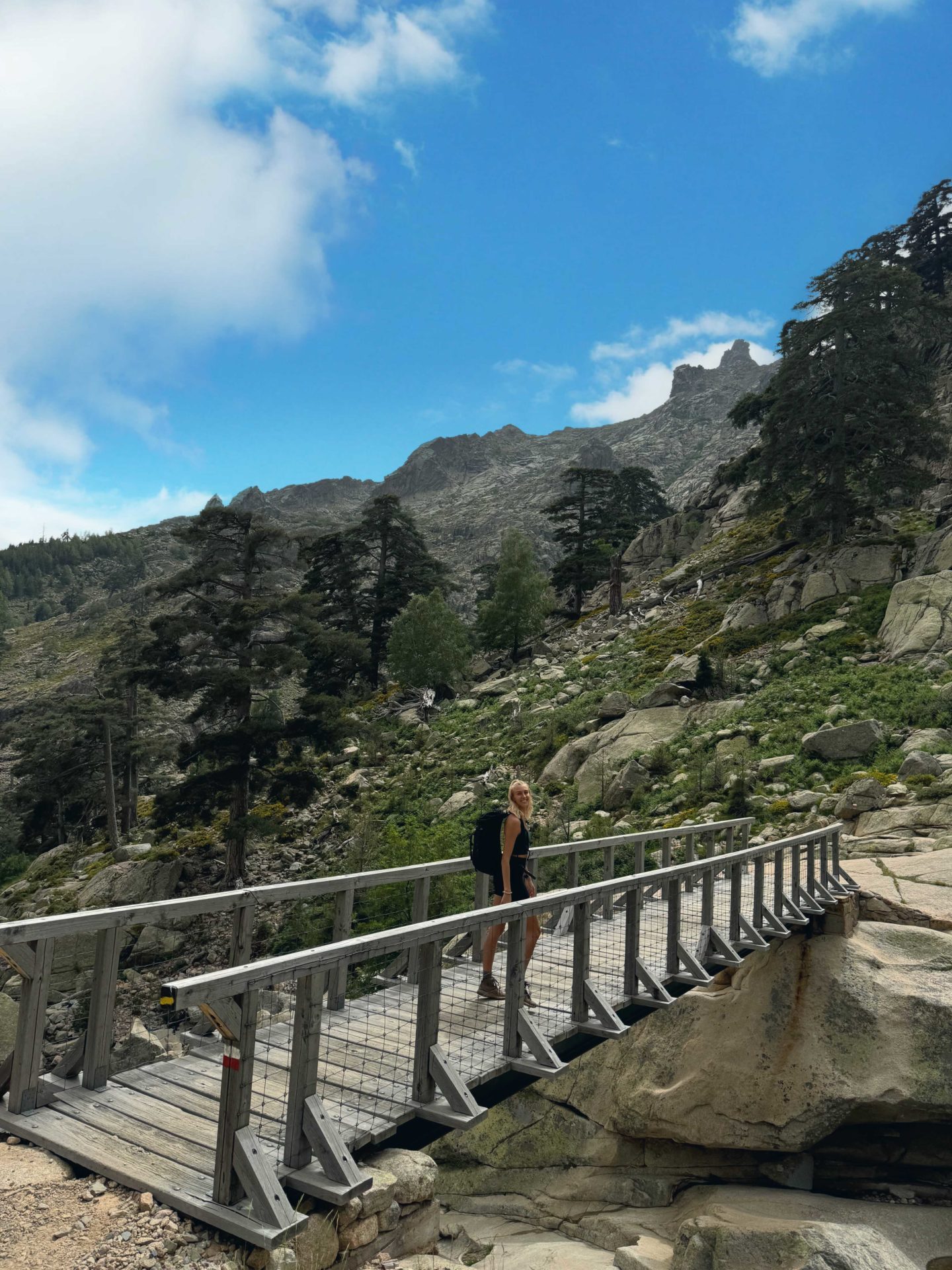 Zanna van Dijk crossing a wooden bridge on a hike in Corsica