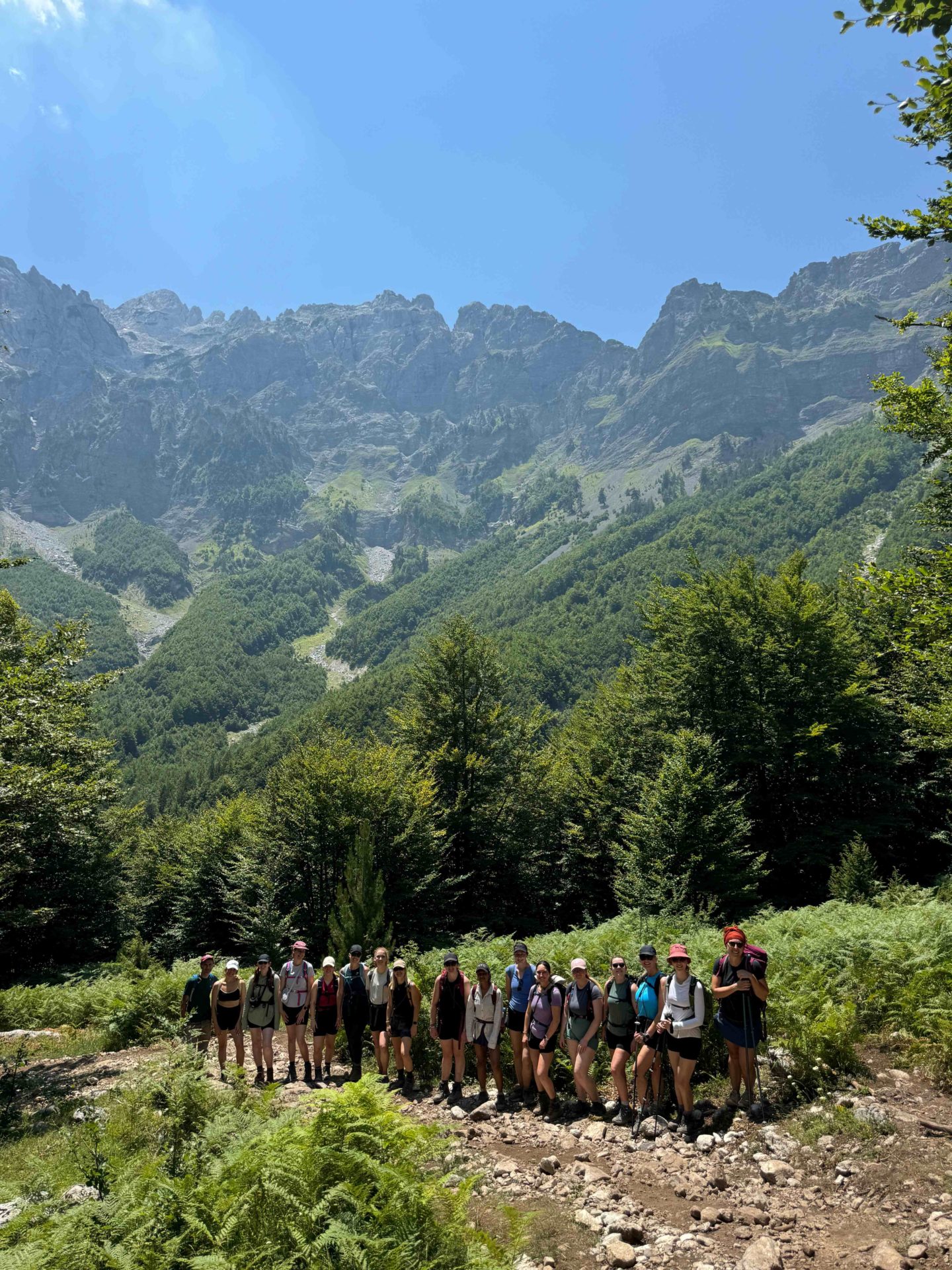 A group of women stand in front of a view point in Albania while on a hike.