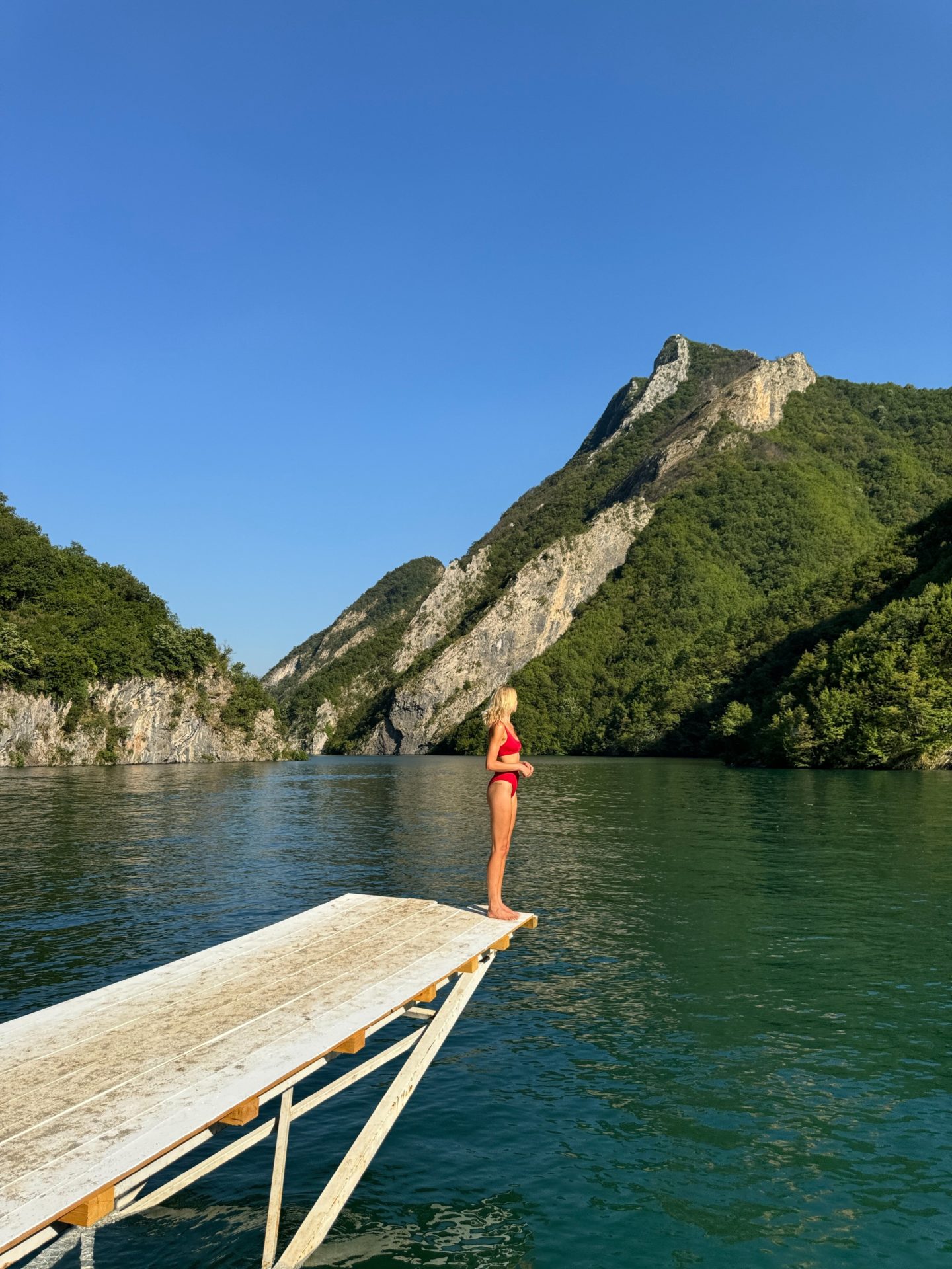 Zanna van Dijk stands on the edge of a jetty looking out across a lake in Albania