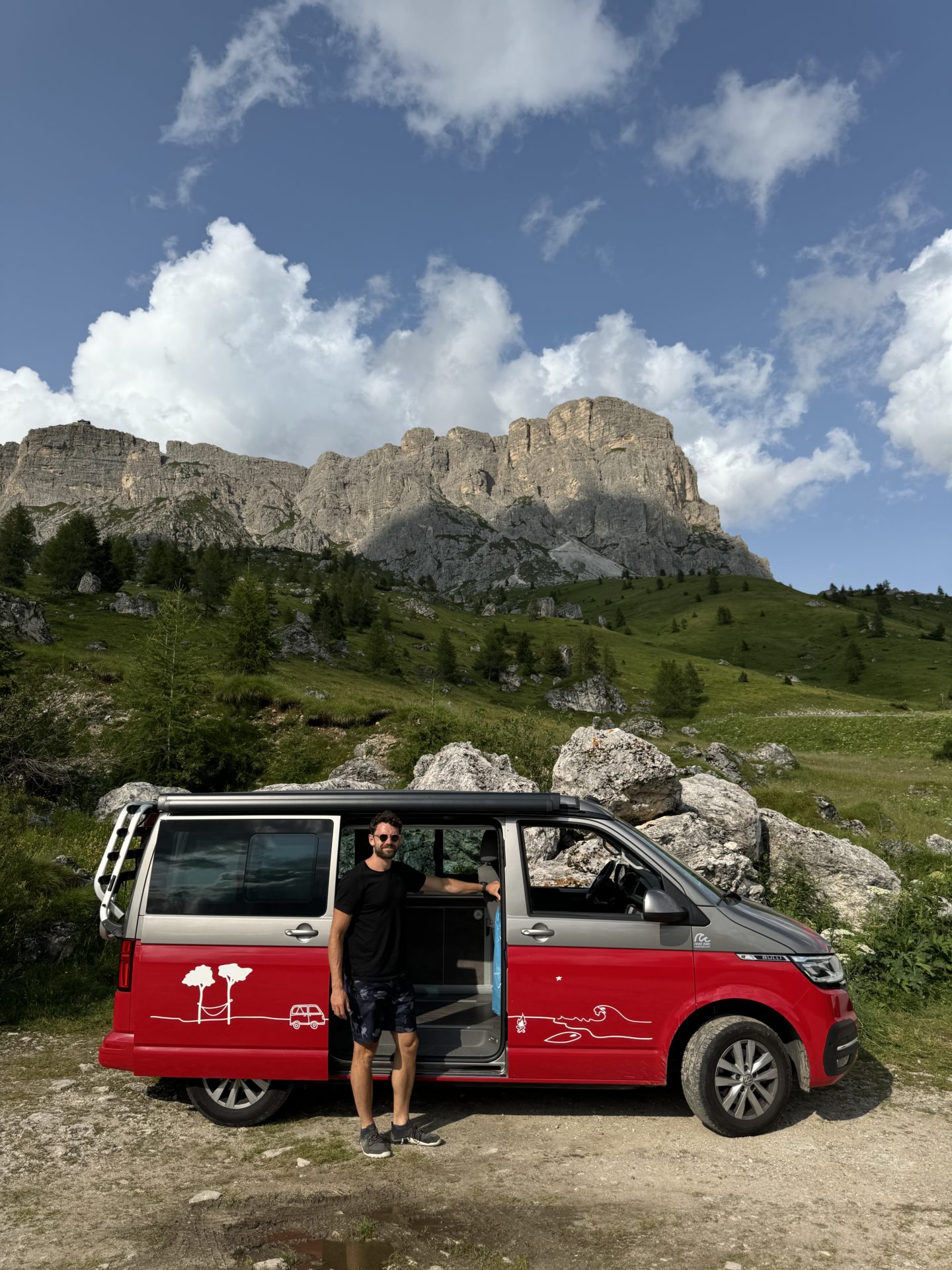 A man stands next to a Roadsurfer camper van in the Dolomites